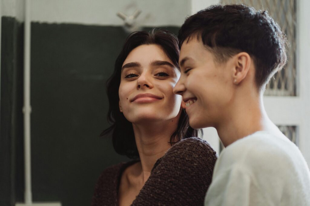 Two joyful women, in a loving embrace, express happiness and togetherness indoors.