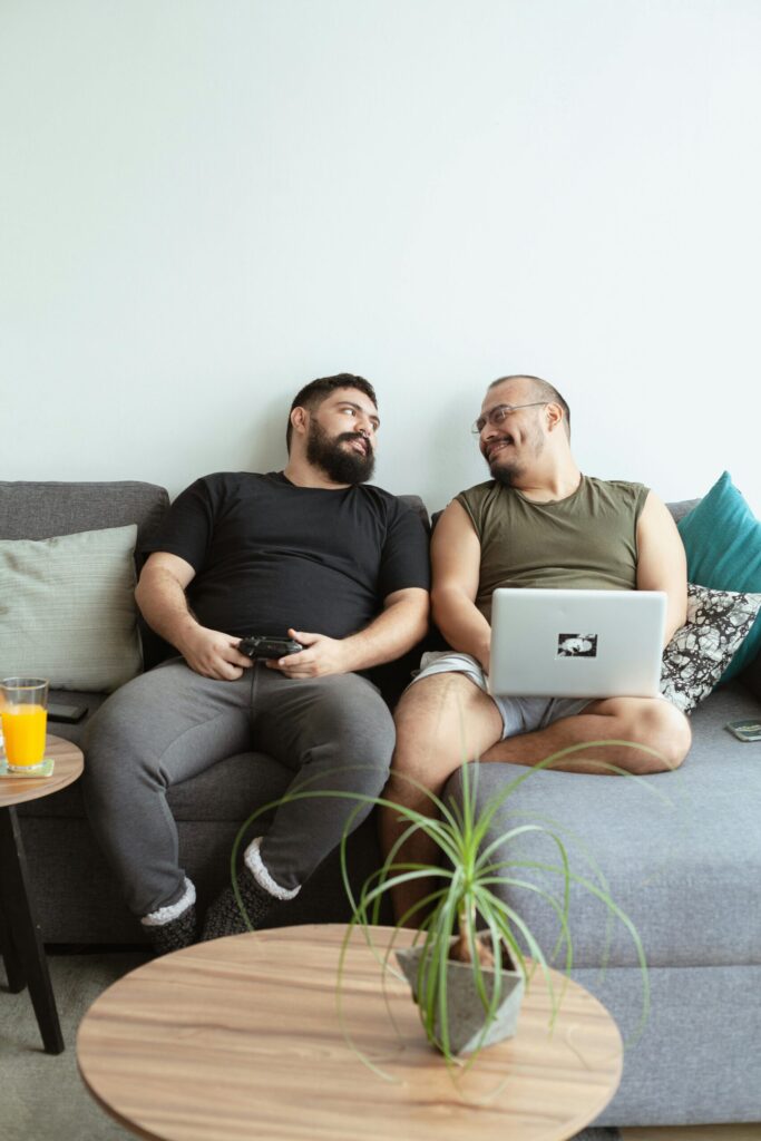 A cheerful couple lounging together on a couch, enjoying technology and each other's company.